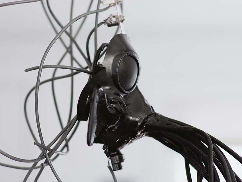 Side view of a gas mask with wires coming out of it. 