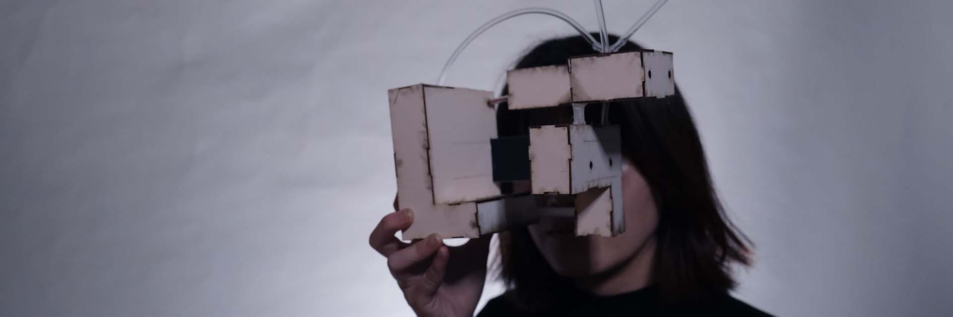 Person holding the device made of a series of boxes and tubes to their face